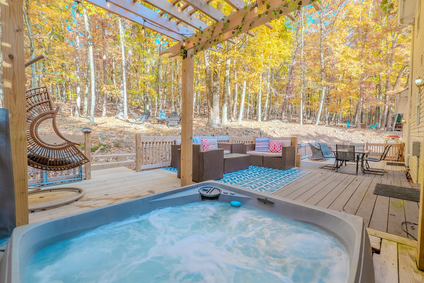 Steaming hot tub on a deck surrounded by autumn trees