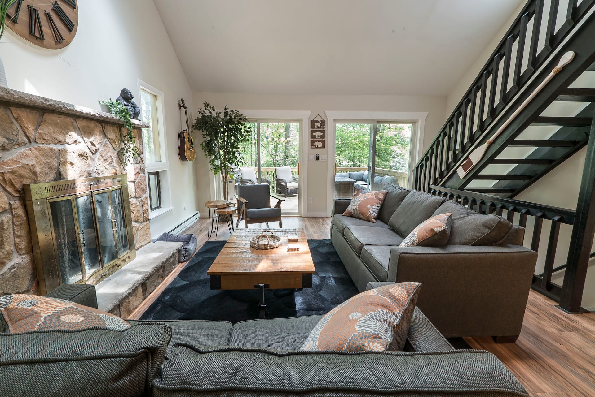 Living room with a stone fireplace and black steel staircase